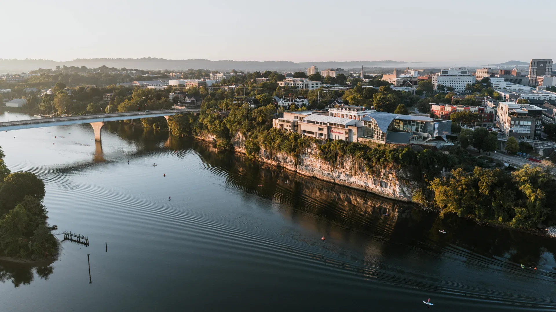 Aerial view of Chattanooga's riverfront area at sunrise showcasing modern architecture and lush greenery. in Chattanooga Scavenger Hunt, TN