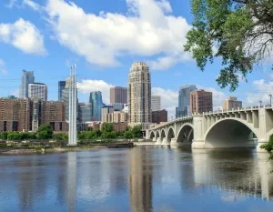A scenic view of Minneapolis skyline with a bridge over the Mississippi River under a clear blue sky. in Minneapolis Minnesota Scavenger Hunt, MN
